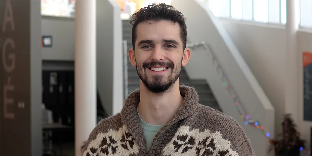 Isaac Vestby smiles at the camera while standing in the atrium of the Student Centre 