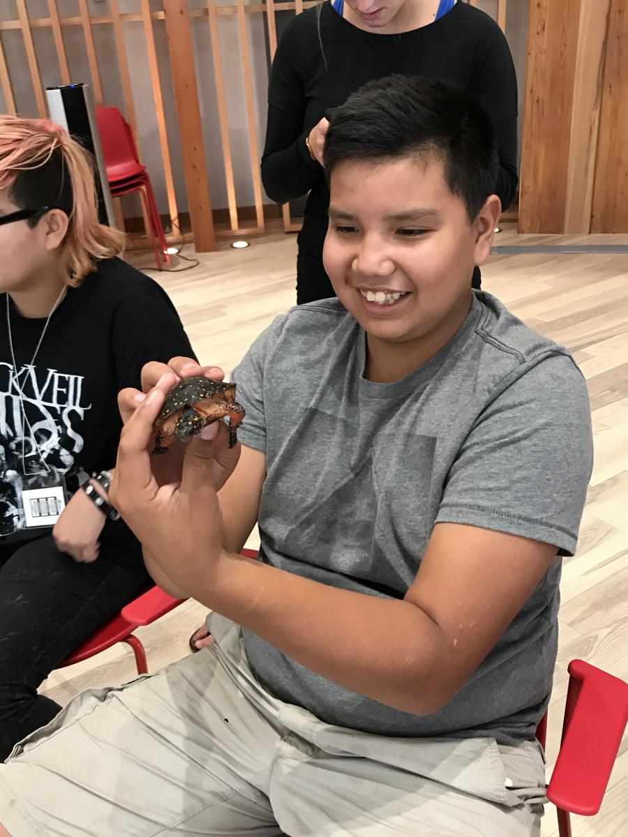 An Indigenous youth holding a turtle 