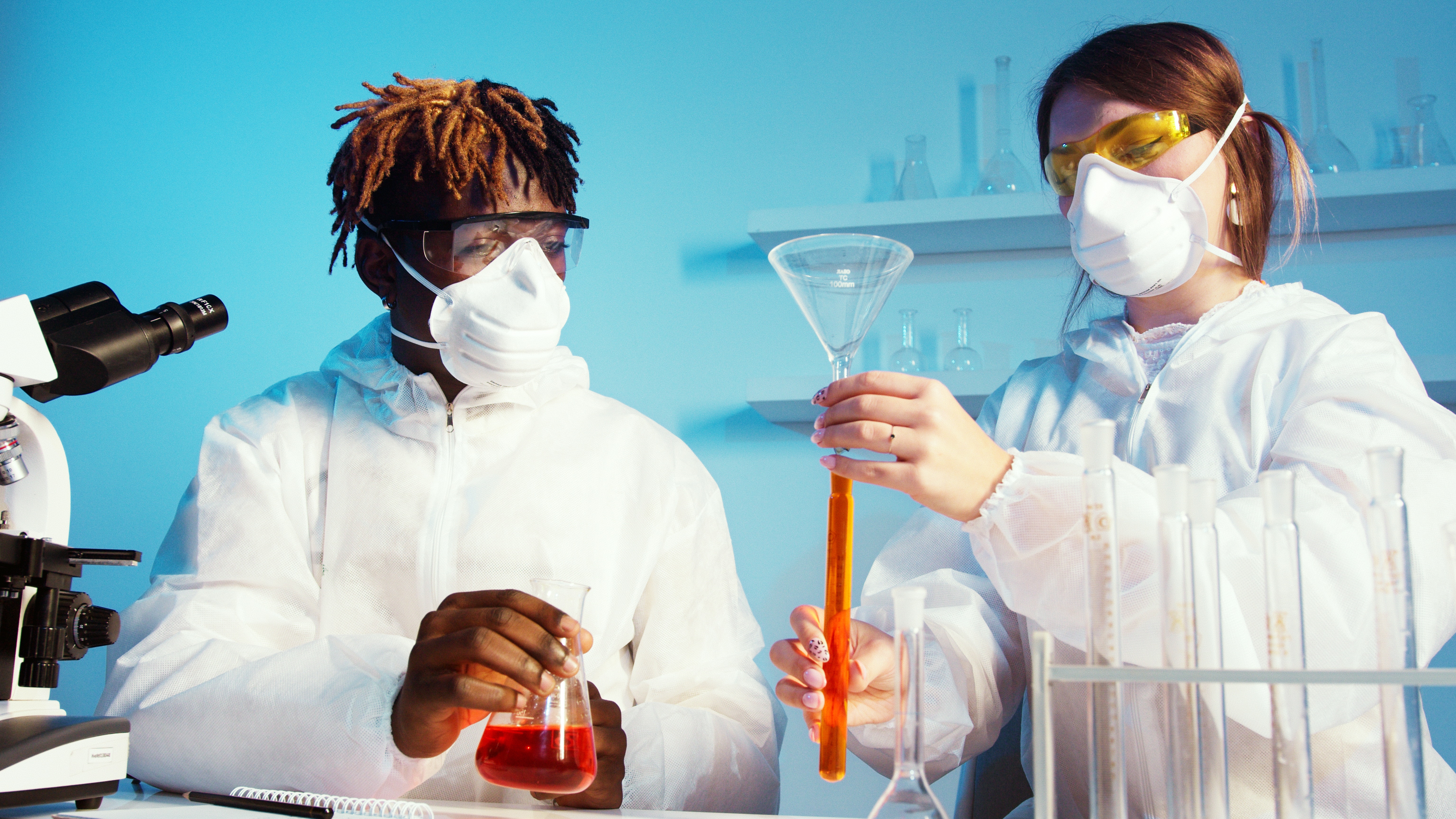 Two students are holding test tubes with different substances in them 