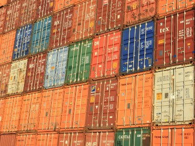 A lot of shipping containers stacked side by side and one on top of each other.