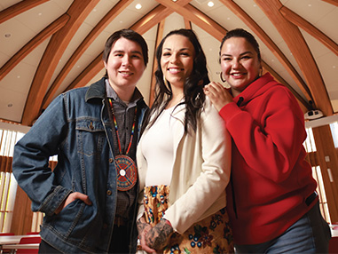 Three members of the Laurentian Indigenous community smiling inside the Indigenous Sharing and Learning Centre 