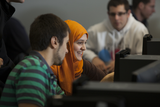 two students smiling while using a computer