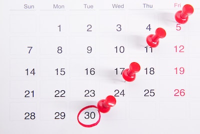 A picture of a calendar with red pushpins next to certain dates and a red circle around the last day of the month.