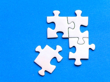 Four white puzzle pieces on a blue background, with three put together.
