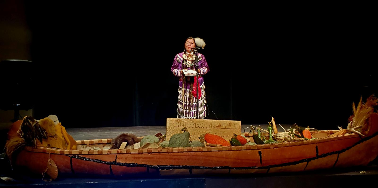 Karen J. Pheasant-Neganigwane standing behind a canoe 