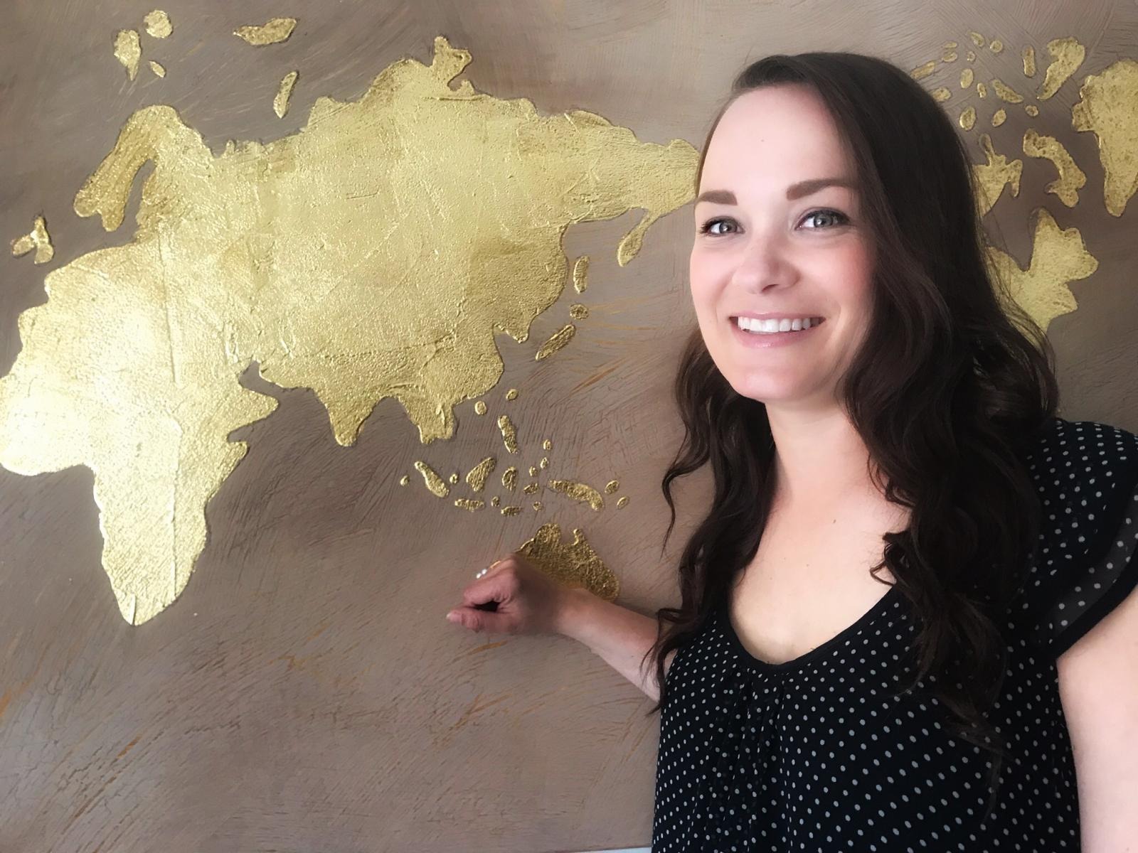  Isabelle Baril smiling in front of a wall with the continents painted on it 