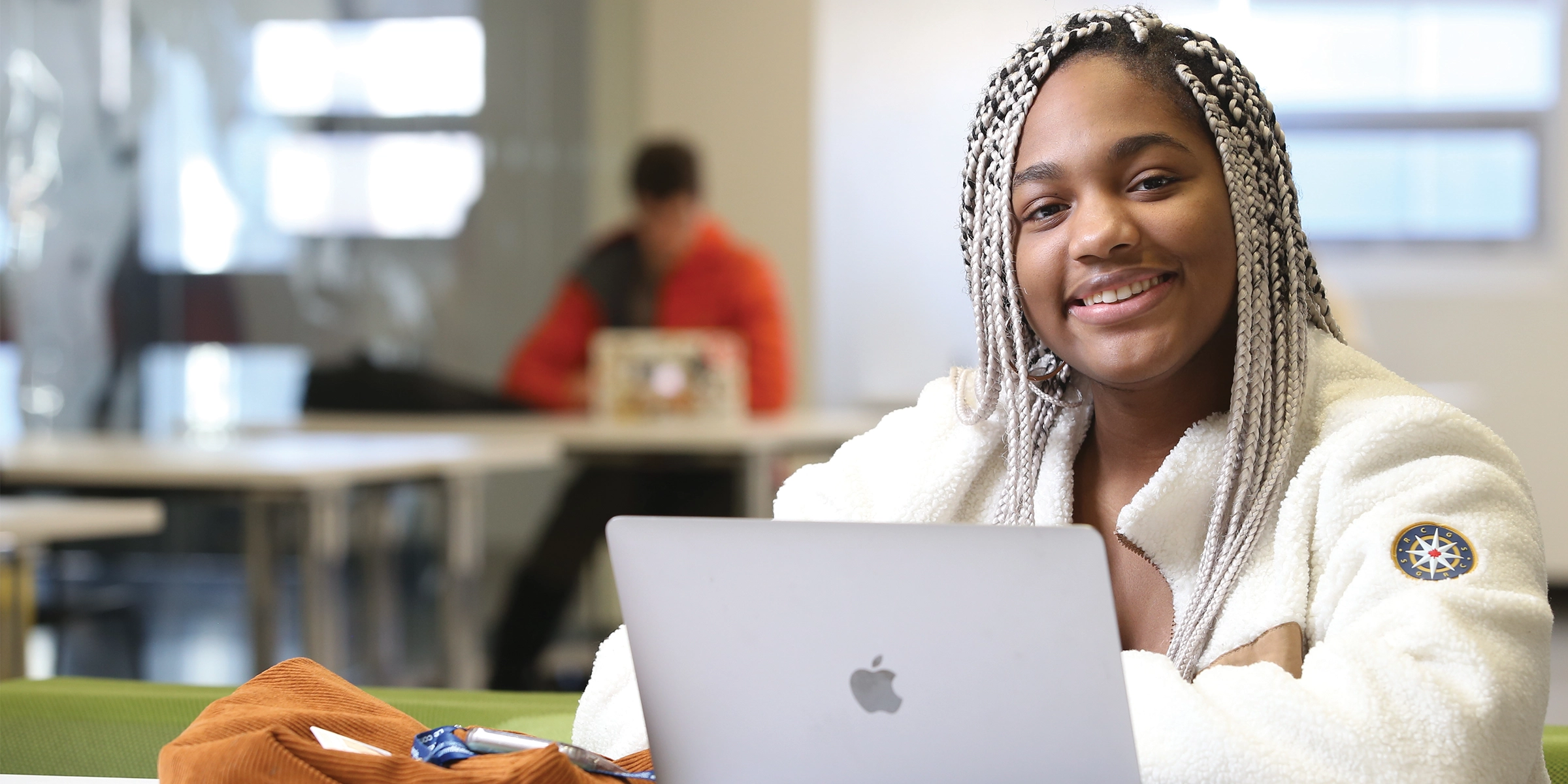 A Laurentian University student smiling and sitting with her laptop open.