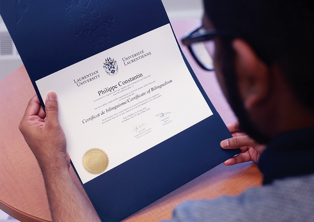  A bilingual Laurentian University student holding their Certificate of Bilingualism.