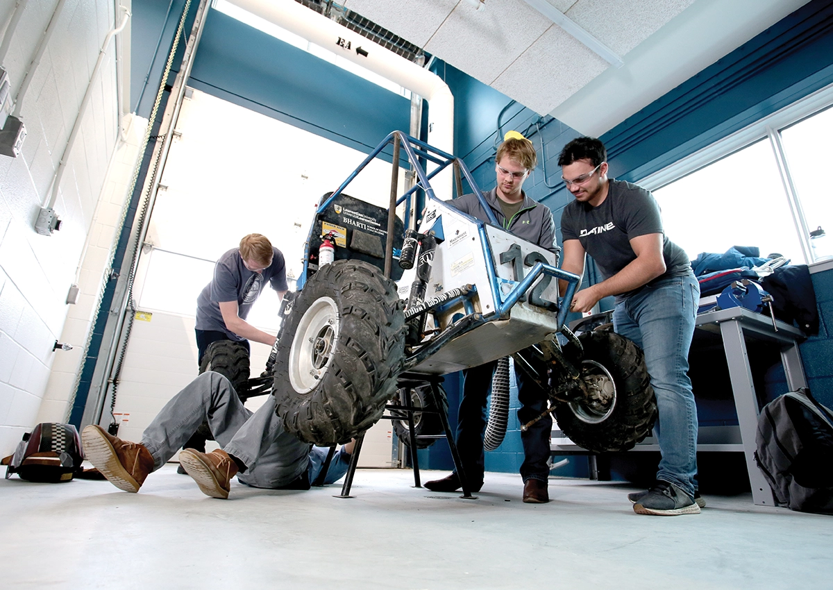 Four Laurentian University students from the Bharti School of Engineering working on a robotic car.
