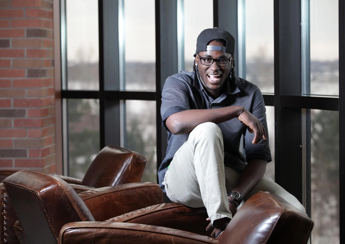 Student sitting on chairs in the Brenda Wallace Reading Room, smiling at the camera.
