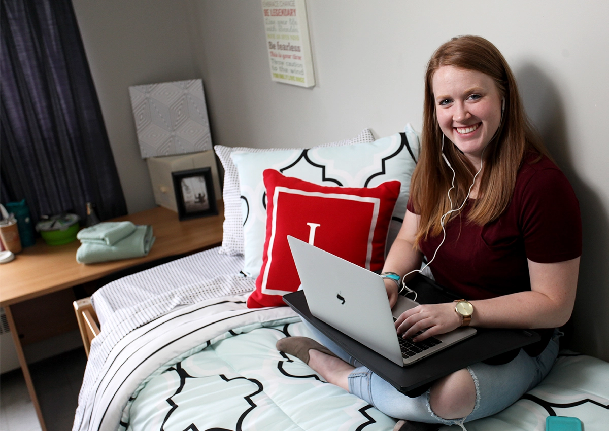 A Laurentian University student in her residence room while on her laptop.