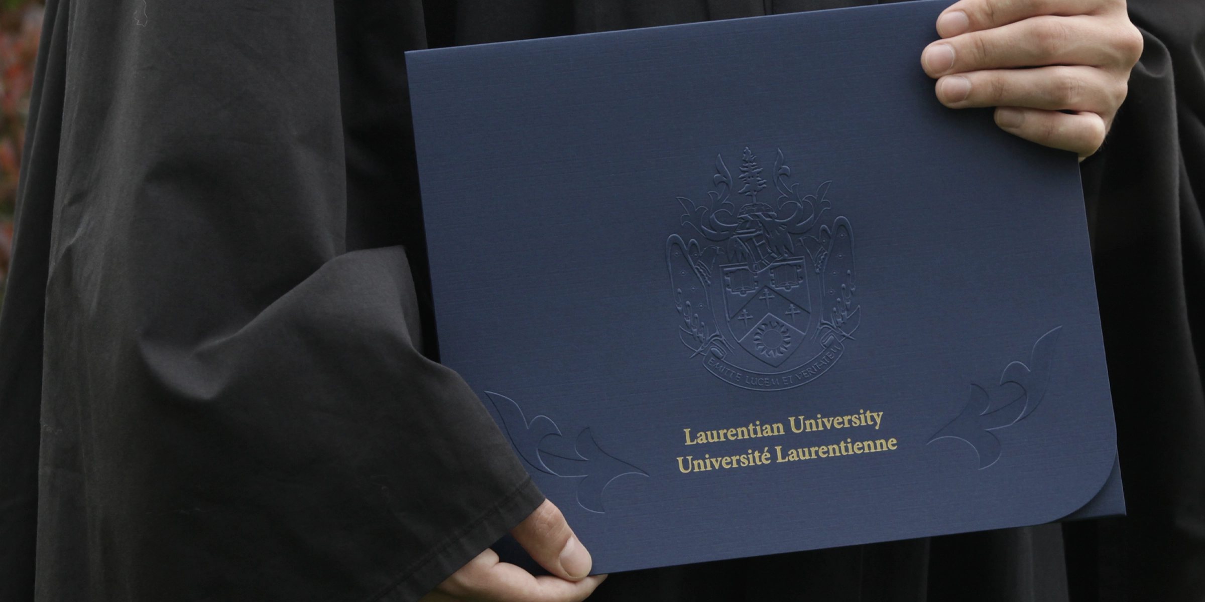 Person holding their degree enclosed in a dark blue Laurentian University envelope.