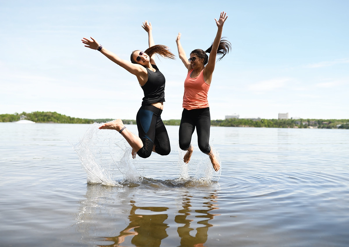 Two Laurentian University students jumping in a lake at Beach Day.
