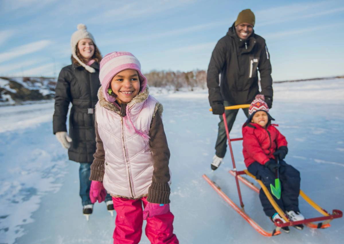A family skating and sledding on the icy terrain of Ramsey Lake in the winter.