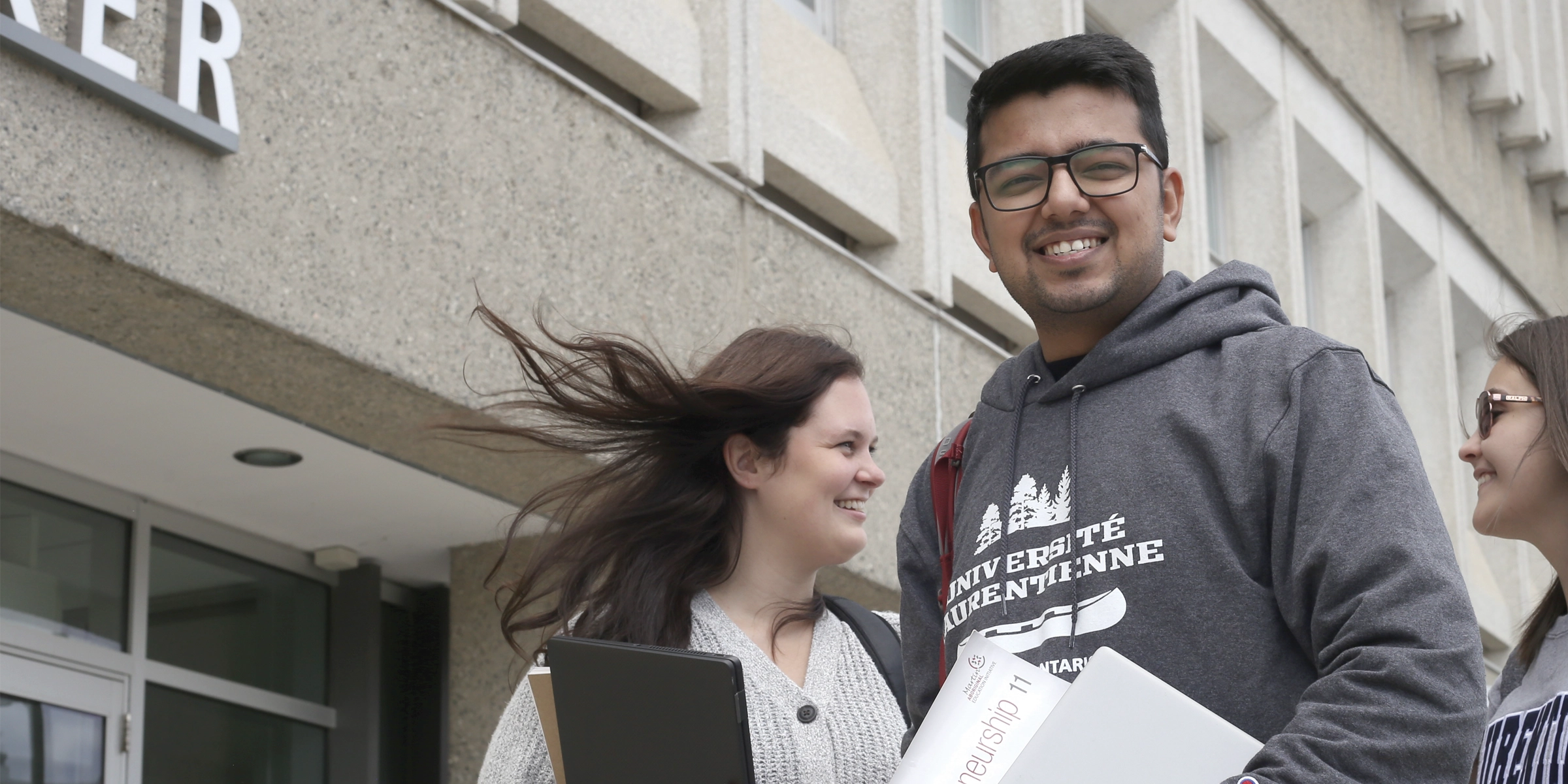 A student smiling at the camera, in front of the Parker Building.