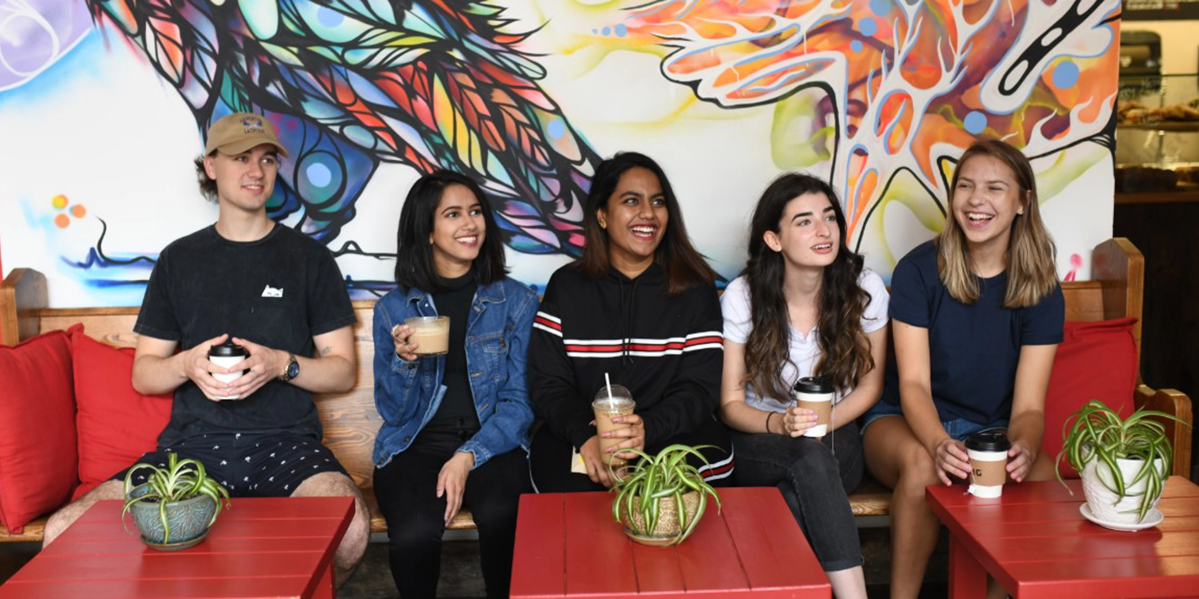 A group of students on a couch with their drinks from a local coffee shop.