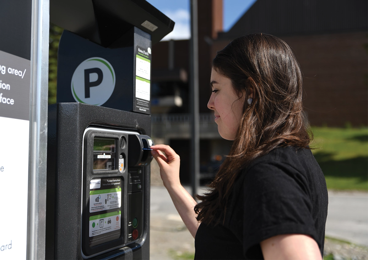 A Laurentian University student paying for parking at a parking meter.