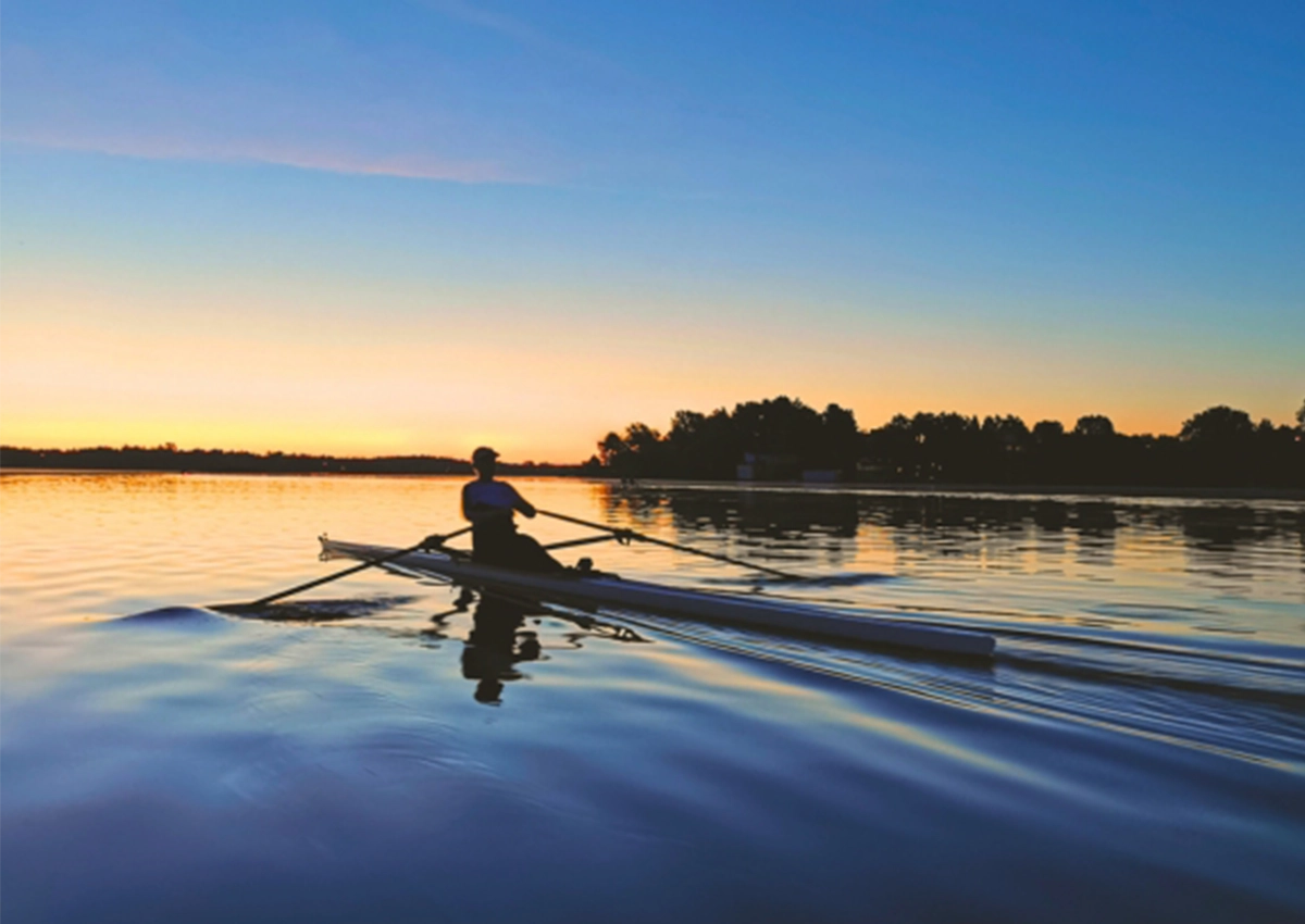 A Laurentian University student kayaking on a lake at sundown.