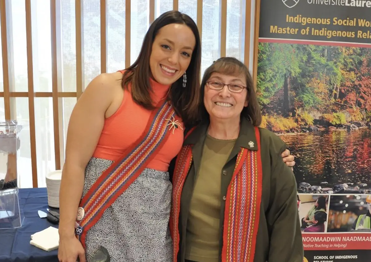 Two women smiling at the camera, with a banner for Laurentian's Indigenous academic programs.