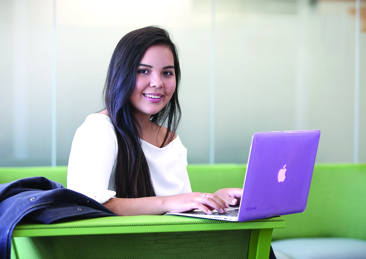 A student smiling while using their laptop