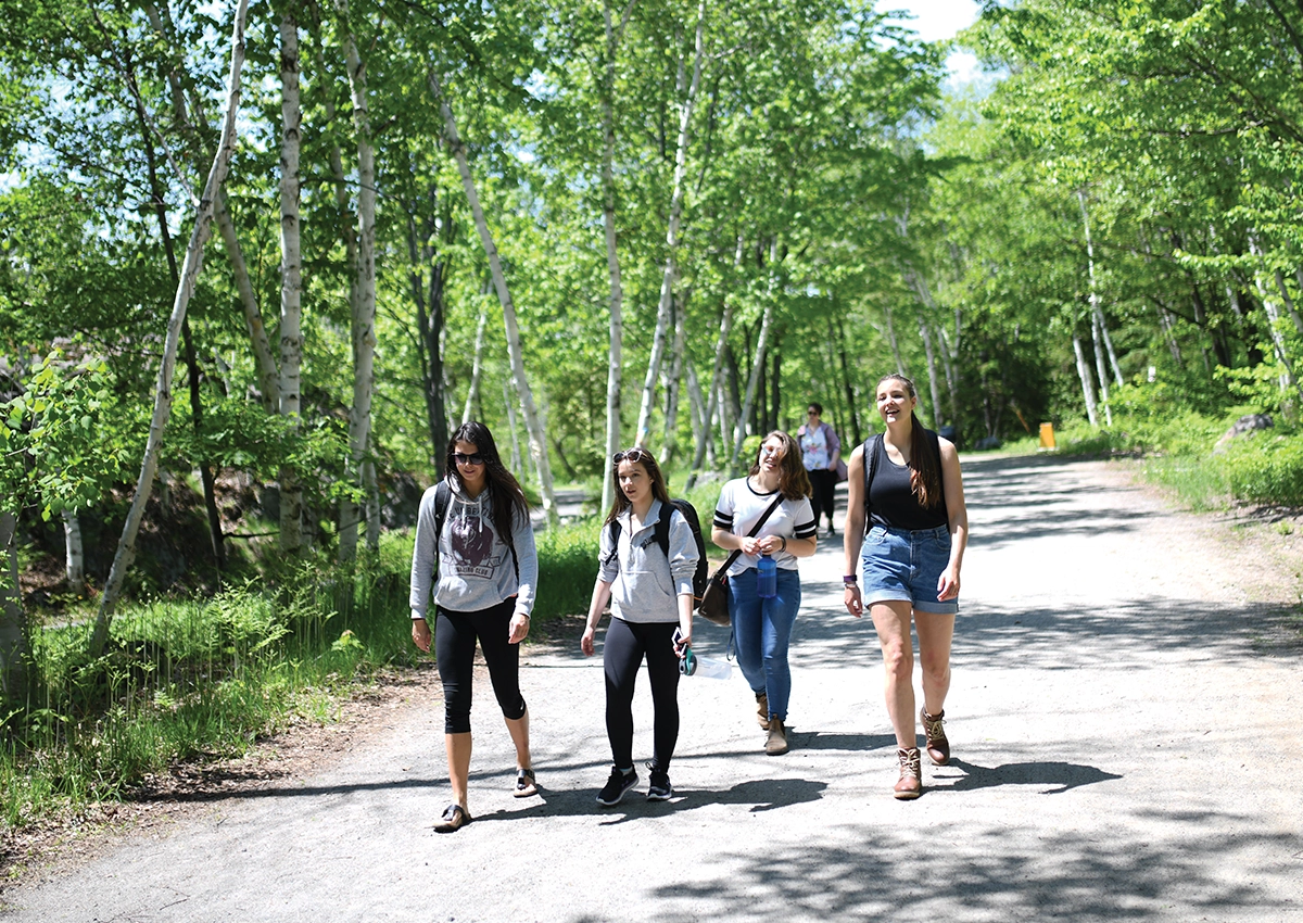 Four Laurentian University students walking on a trail on campus.