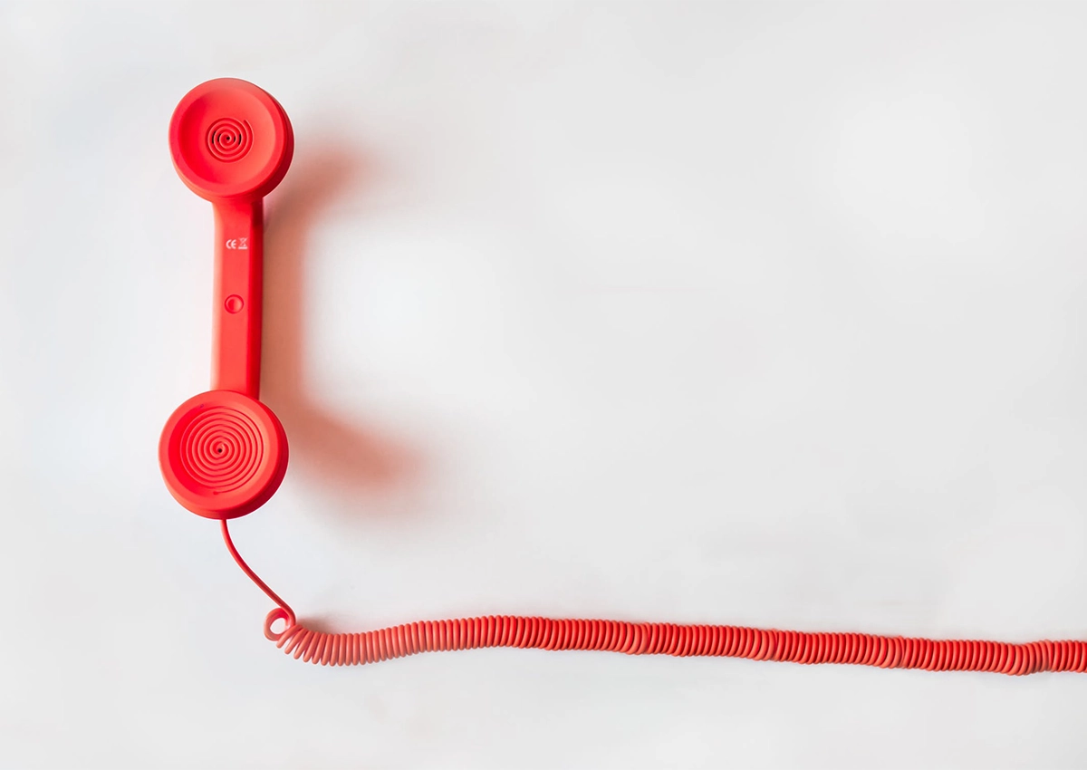 A red corded telephone on a white background.