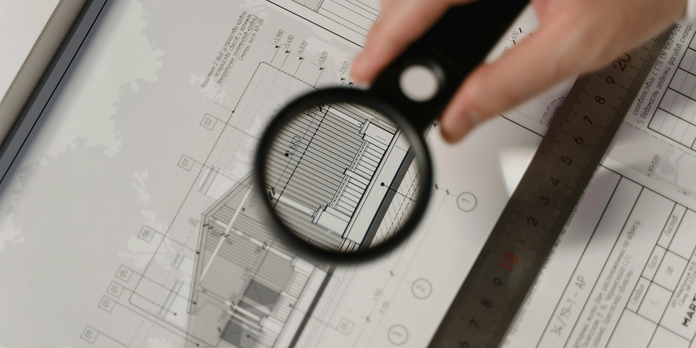 Someone looking at a blueprint with a magnifying glass.