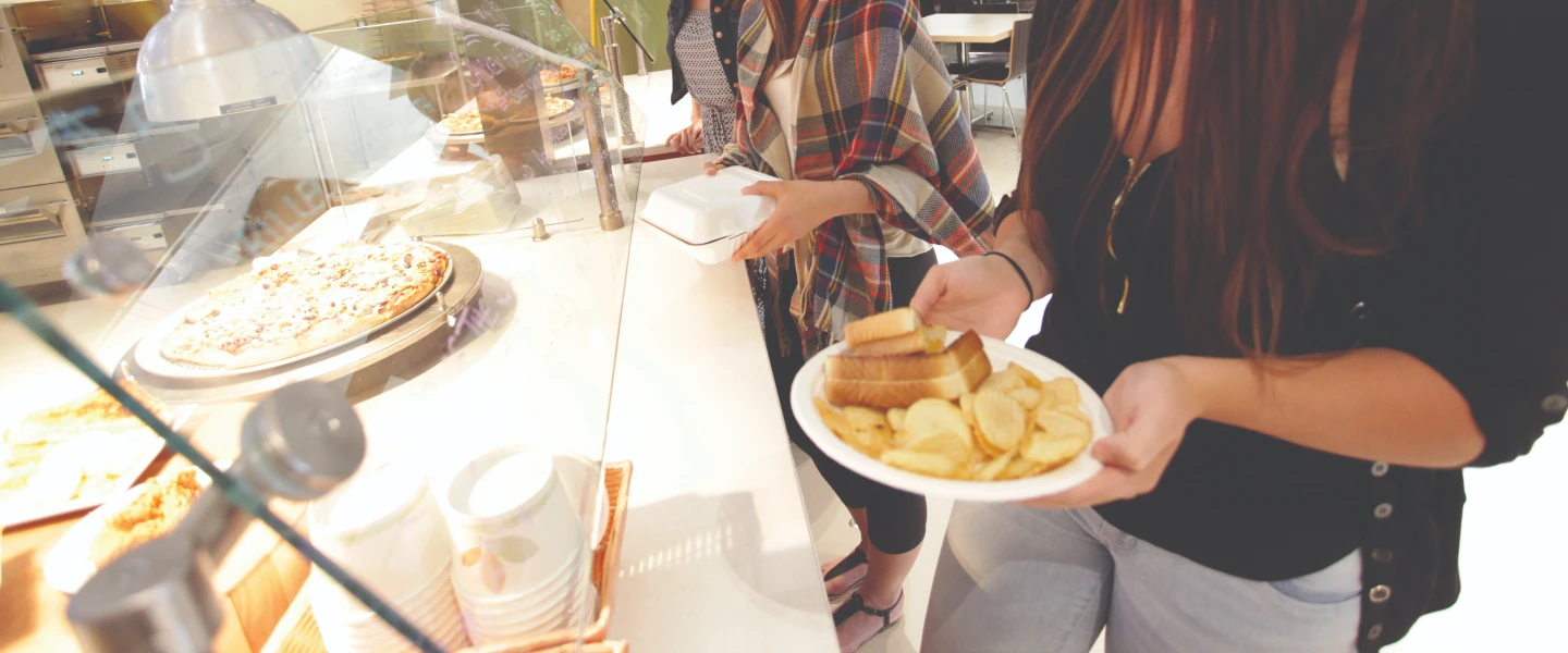 Two pairs of hands holding a plate full of food by the lunch buffet.