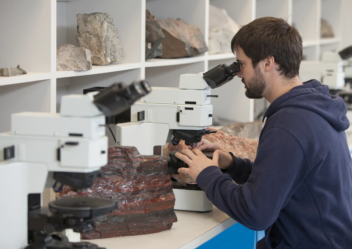 A Laurentian University student examining rocks through a microscope.