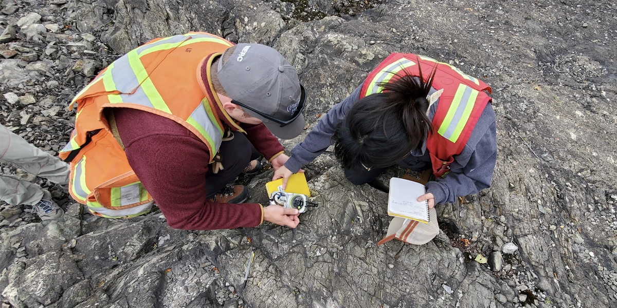 Two Geology students examining rocks in a field.