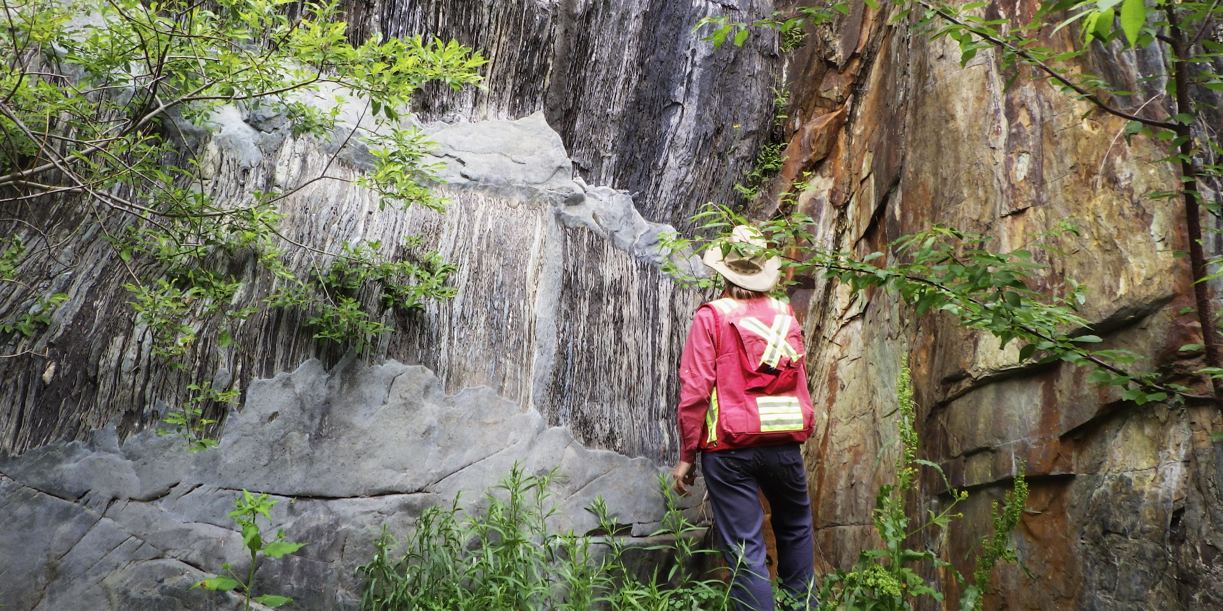 A Laurentian University Geologist examining a wall of rock formations.