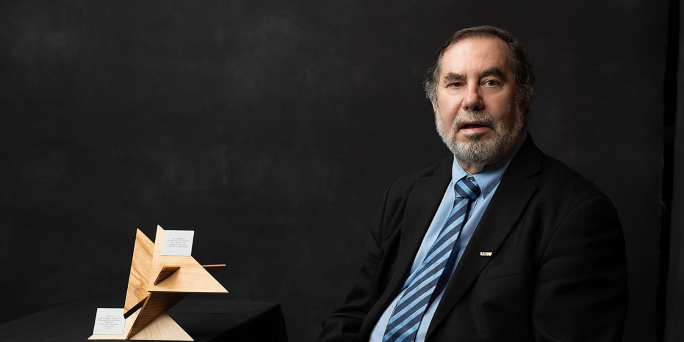 Dr. Leo Gerard poses for a professional headshot, dressed in business attire against a dark background.