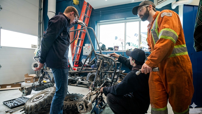 3 people working with a project in the Machine shop