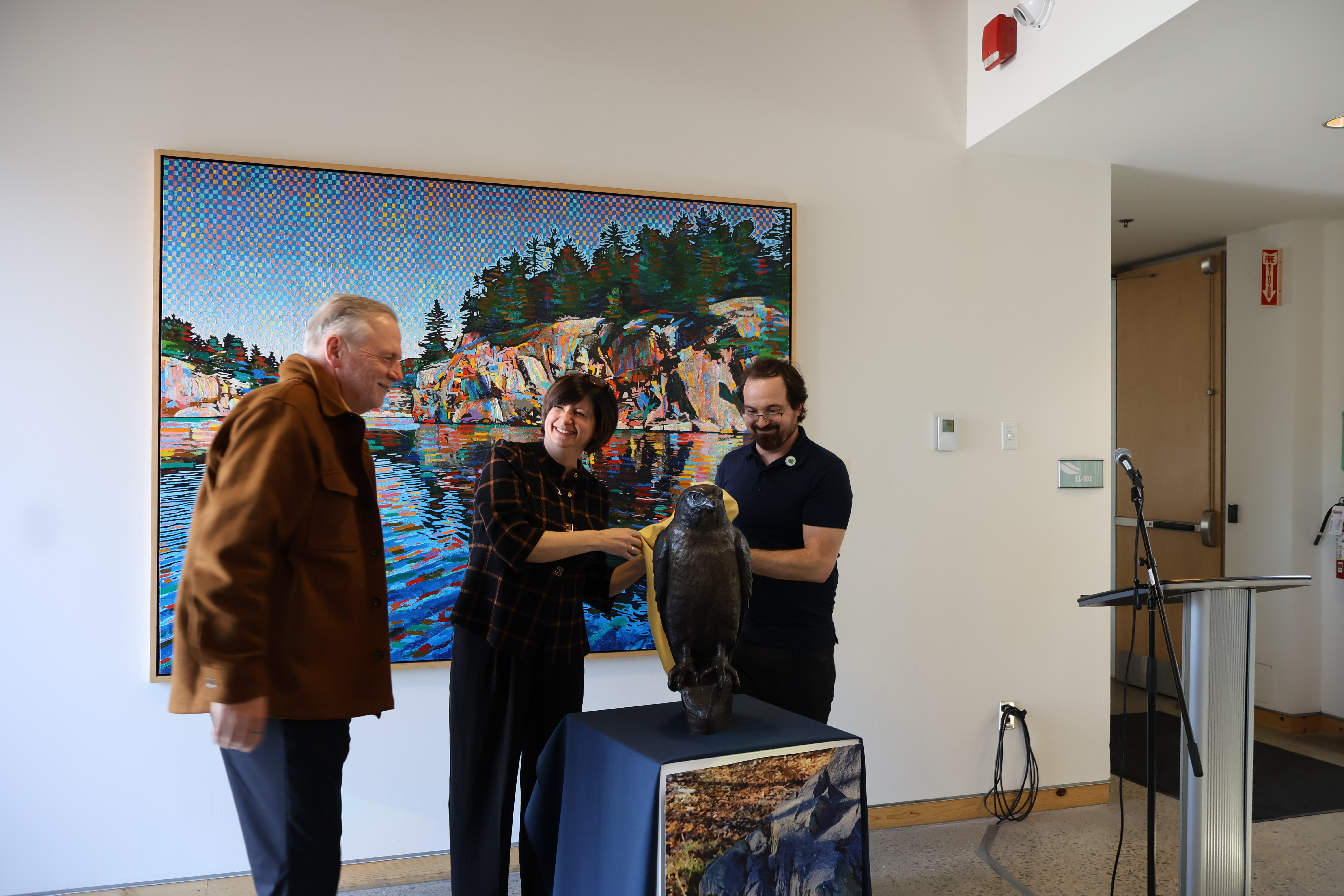 Laurentian University representatives and sculptor Tyler Fauvelle unveil the "Reasons for Hope" bronze sculpture. Depicting a peregrine falcon, the artwork stands as a symbol of conservation and environmental recovery at the Vale Living With Lakes Centre.