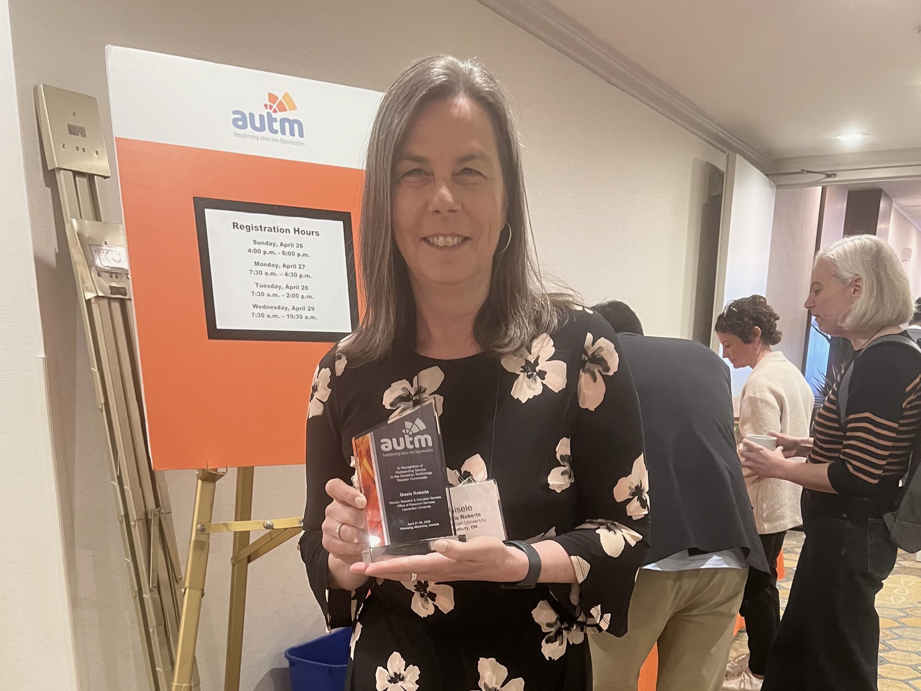 Gisele Roberts, Director of Research and Innovation, smiles while holding her AUTM Canadian Award for excellence in technology transfer.