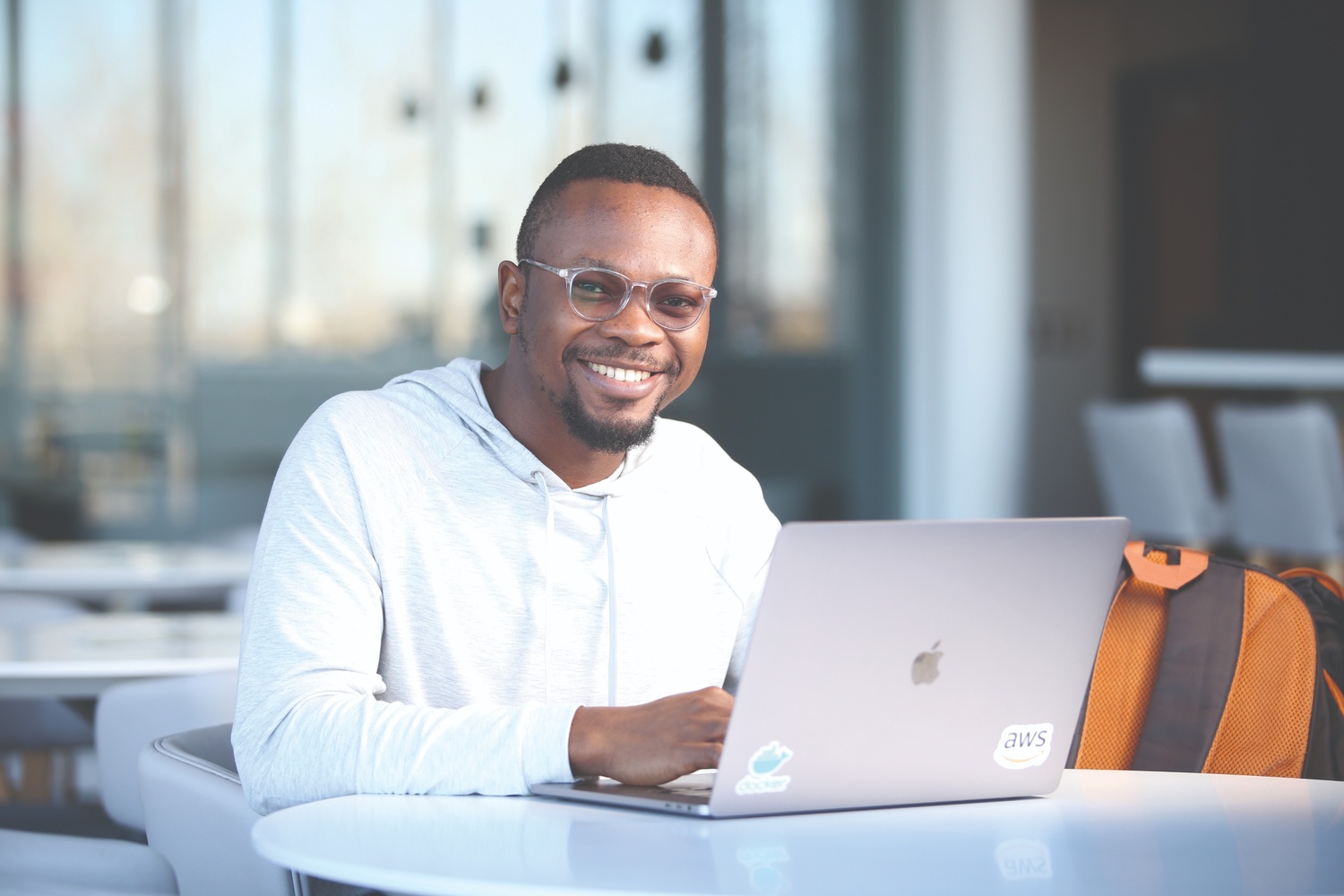 A student smiles behind a laptop. 