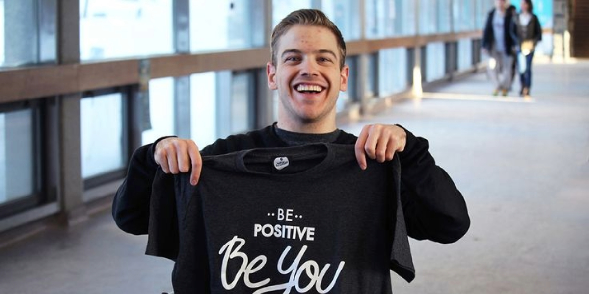Ryan Benoit proudly smiles in the hallway of Laurentian with his Positive Inception shirt.