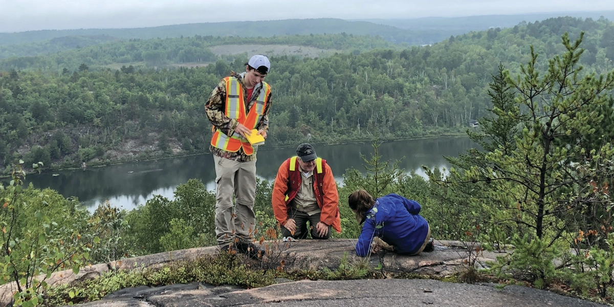 A pair of earth science students working in the field with their professor.