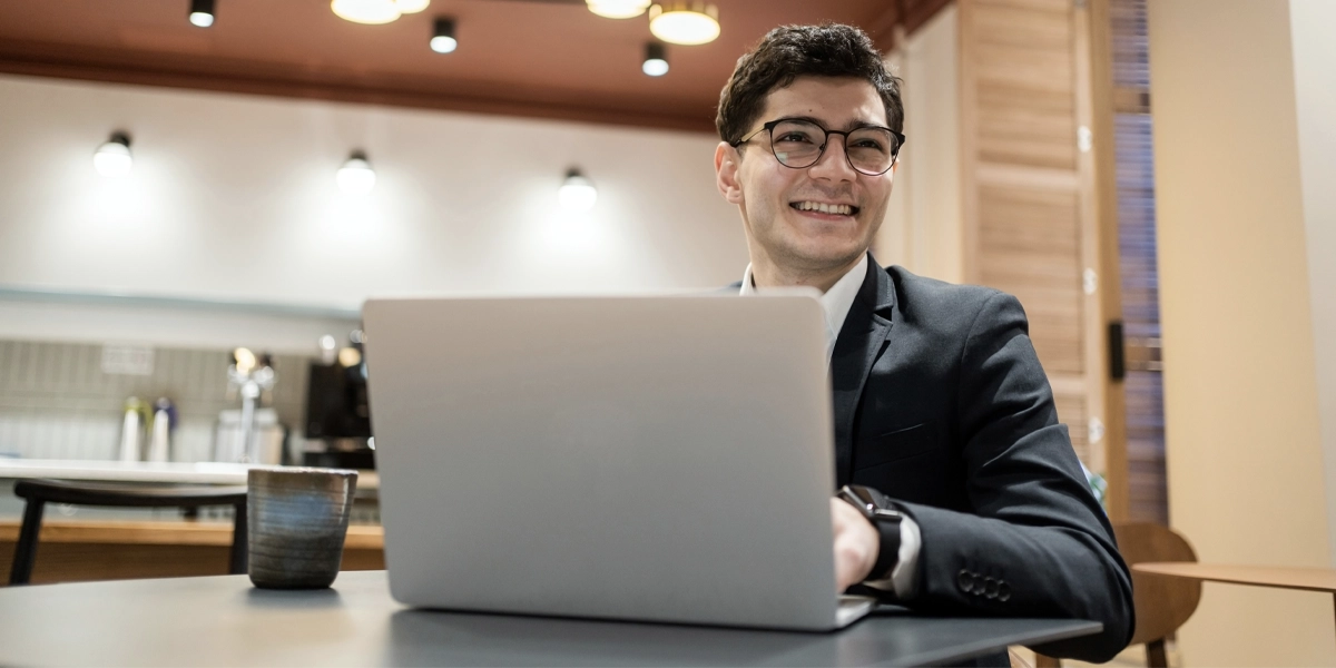 A young man wearing a suit working on a laptop.