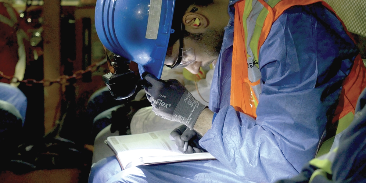 Mining student working in the mines, looking at a notebook.