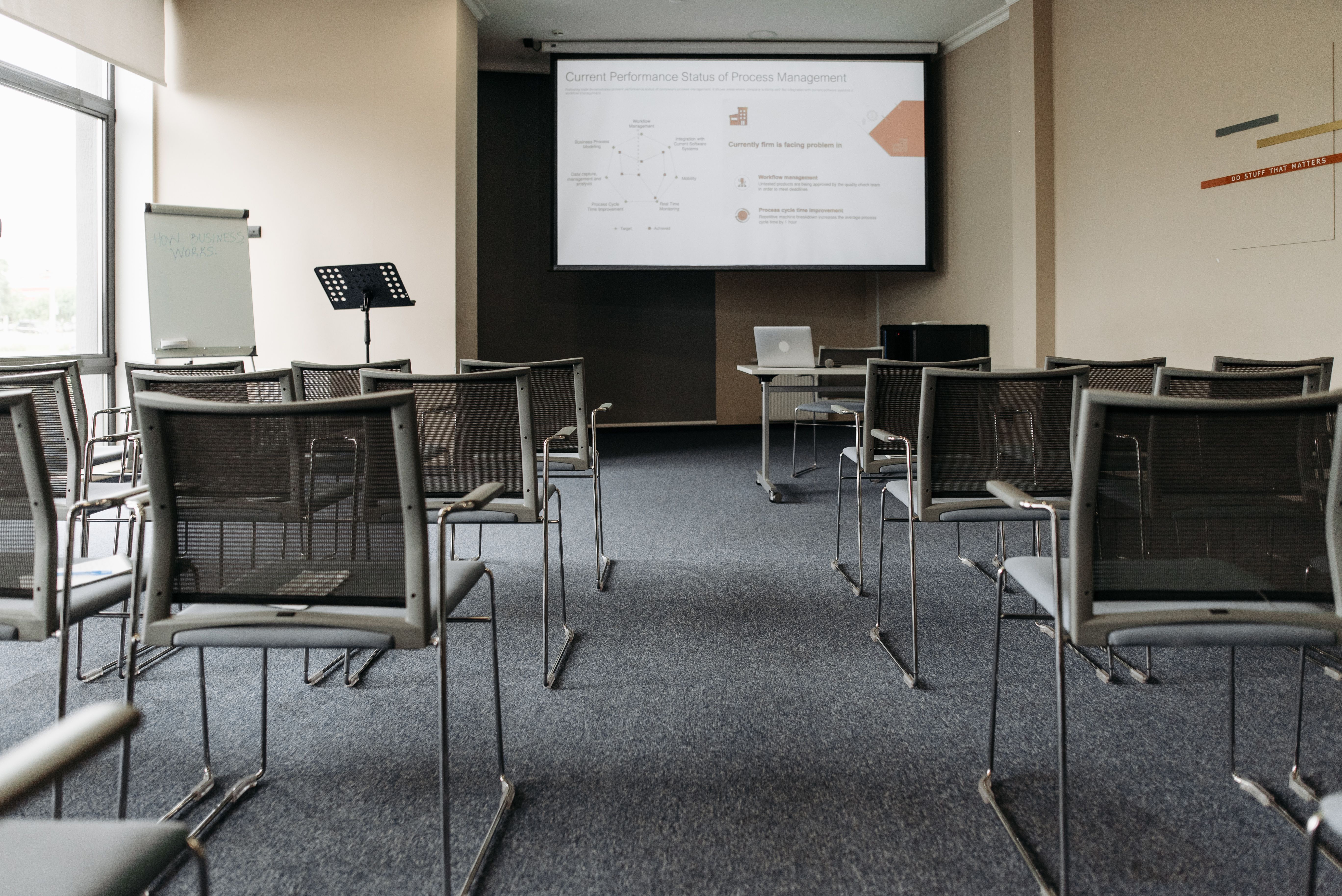 An empty classroom with desks, chair, and a presentation on a screen.