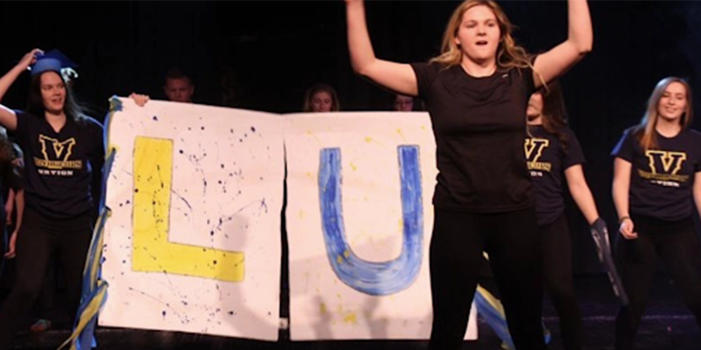 Students holding up a homamde LU sign