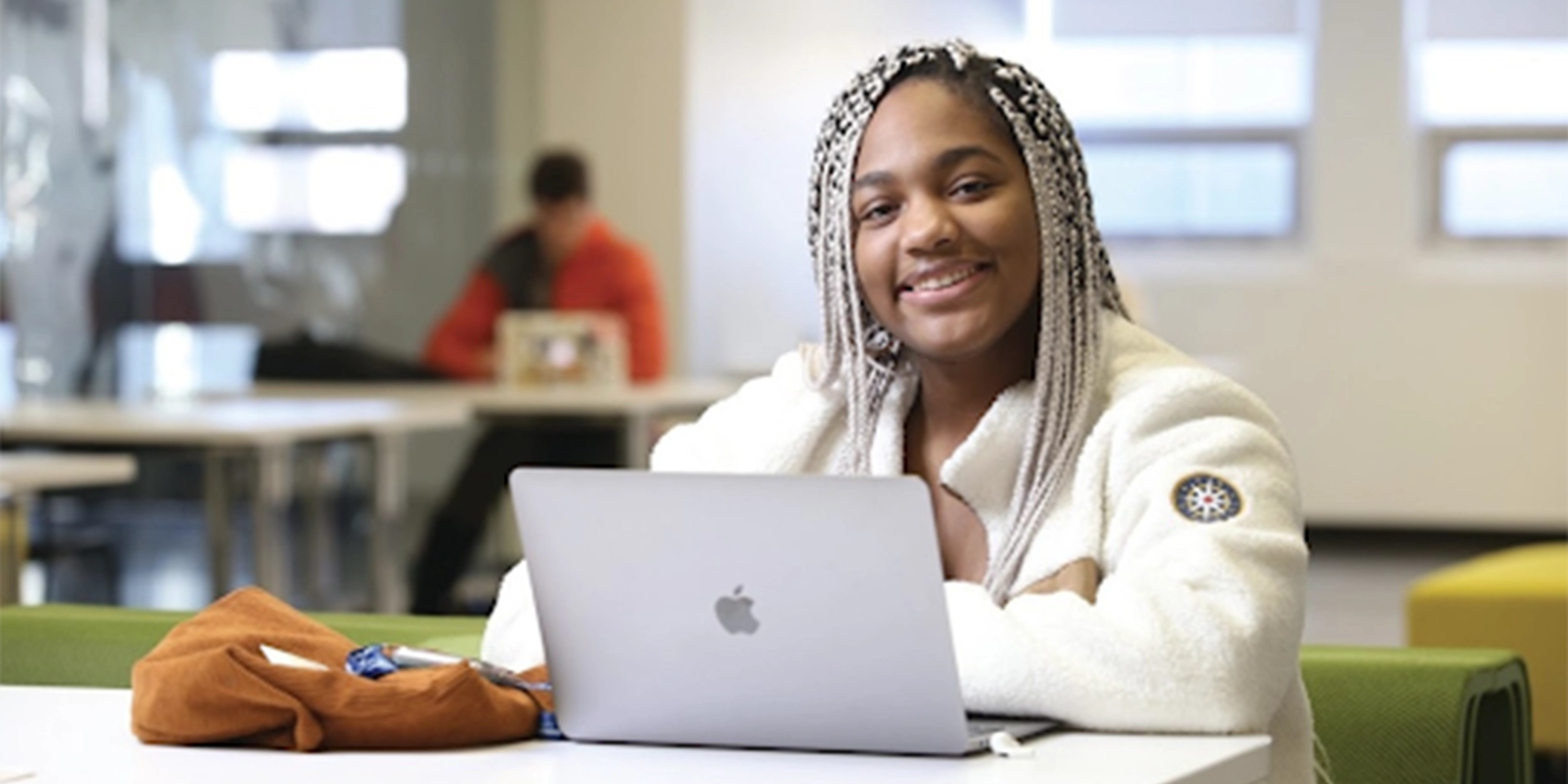 Student with laptop smiling at camera
