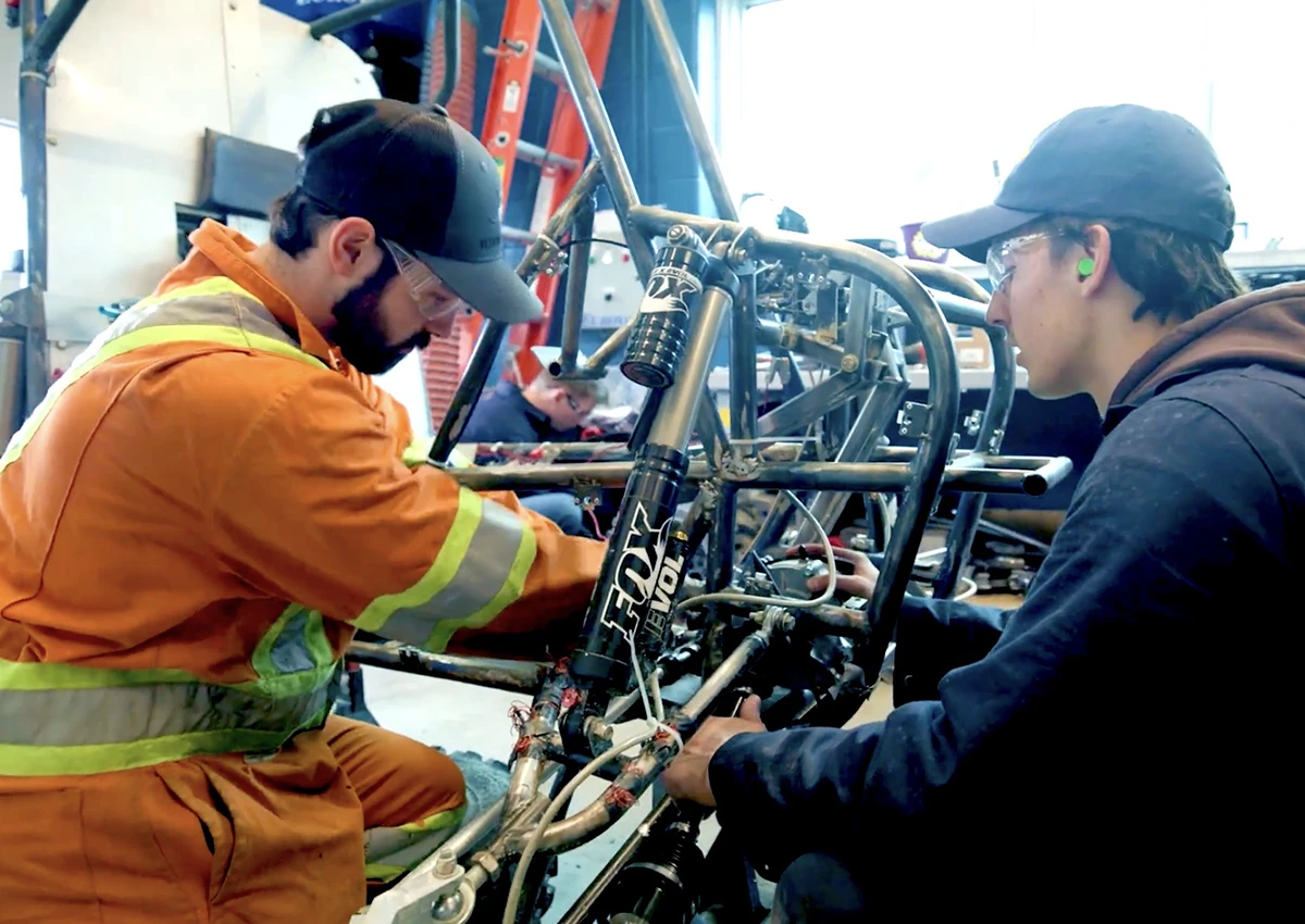 Two Laurentian University Engineering students working on a vehicle.