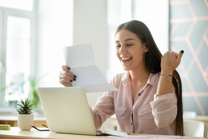 A student reading information on a page while smiling 