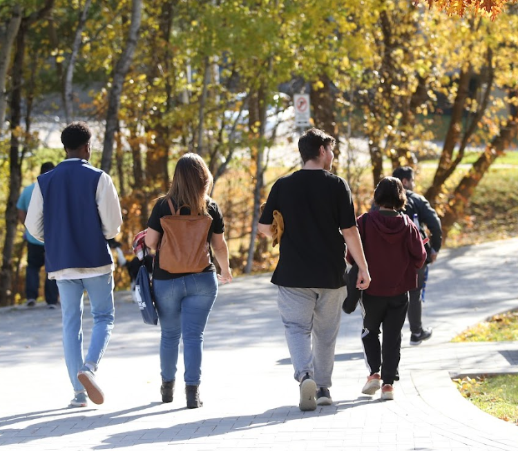 Five Laurentian University students walking on campus to class.