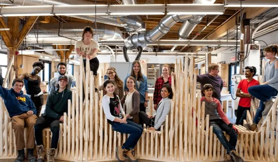 architecture students sit on top of a wooden sculpture in the school of engineering