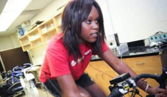 A woman riding a spin bike in a research lab.