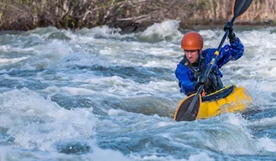 Two men kayaking on a river.