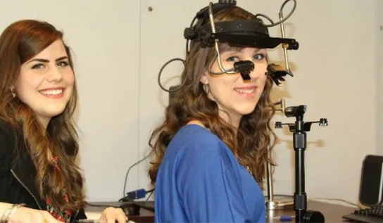 2 psychology students stand in a lab doing an experiment. 